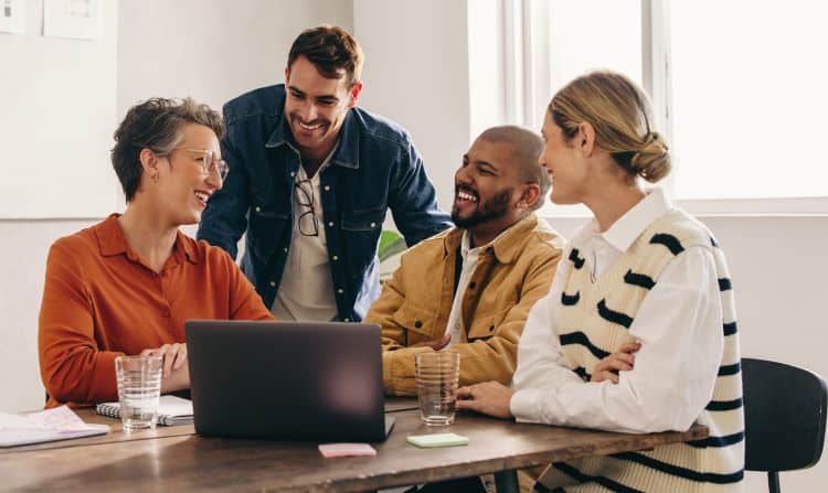 AdobeStock_536917849_resized Team huddled around laptop collaboarting